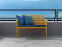 Sofá Net Bench en mostaza con cojines azules, en una terraza – Nardi