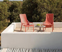 Mesa auxiliar Spritz con sillones Net Lounge en coral, en una terraza – Nardi