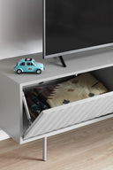 Mueble TV SIERRA de 140 cm con 1 puerta y 3 cajones, en gris, con la puerta abatible abierta bajo la tele – Teulat