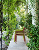 Sillas Doga Armchair en marsala apiladas, en un pasillo con vegetación – Nardi