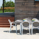 Mesa Alloro 140 extensible en tortora y blanco con sillas, en un patio – Nardi