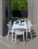 Mesa Rio 140 extensible en blanco con sillas, bajo una pérgola – Nardi