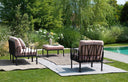 Sillones KOMODO en antracita con cojines rosa cuarzo, en un jardín con piscina – Nardi