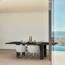 Silla tapizada ADD con pie giratorio cromado, en gris claro, en un comedor con vistas al mar – Teulat