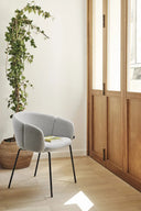 Silla ADD con reposabrazos y patas negras, en gris claro, junto a una ventana – Teulat