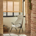 Butaca DINS de respaldo alto con patas de metal negro, en crema, junto a una ventana – Teulat