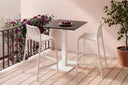 Mesa SAMIRA Cuadrada 70×70 Porcelánica, alta 96 cm, negro, blanca, en una terraza