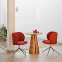 Silla tapizada MOGI con pie giratorio cromado, en teja, junto a una mesa redonda de madera – Teulat