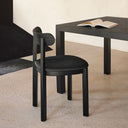 Silla NARA con asiento tapizado en negro, junto a una mesa negra – Teulat