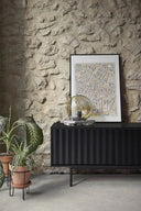 Mueble TV SIERRA de 180 cm con 3 puertas, en negro, en un salón con pared de piedra – Teulat
